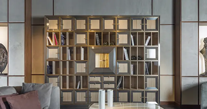 Una parete di librerie Quadro a caselle, in legno e cuoio, con i libri e gli oggetti.