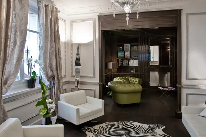 Il salone dell'Hotel Ares Eiffel con le boiserie scure, le poltrone verdi e le librerie.