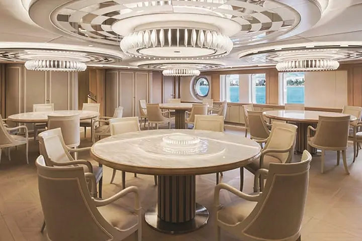 Il salone dello yacht Dream con il tavolo rotondo, le poltrone e il soffitto a cerchi.