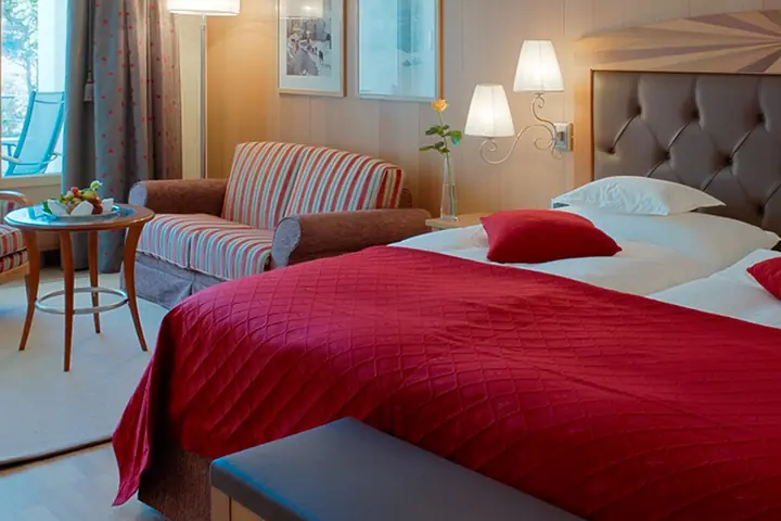 Una camera del Grand Hotel Kronenhof con il letto, le poltrone e il legno chiaro.