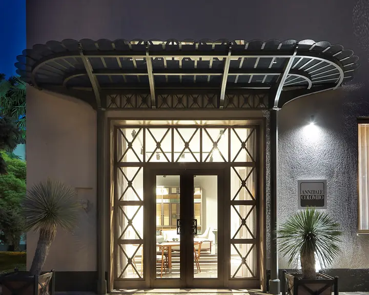 L'ingresso dello showroom di Meda di sera, con la pensilina e le vetrate accese.